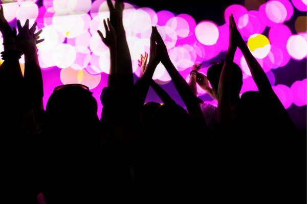People in crowd at concert with pink lights behind